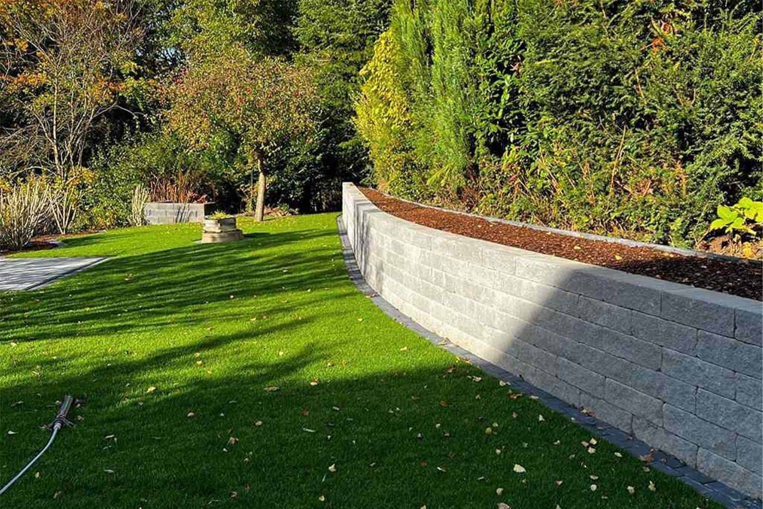 Garten mit Rasen und Mauer aus Natursteinblöcken